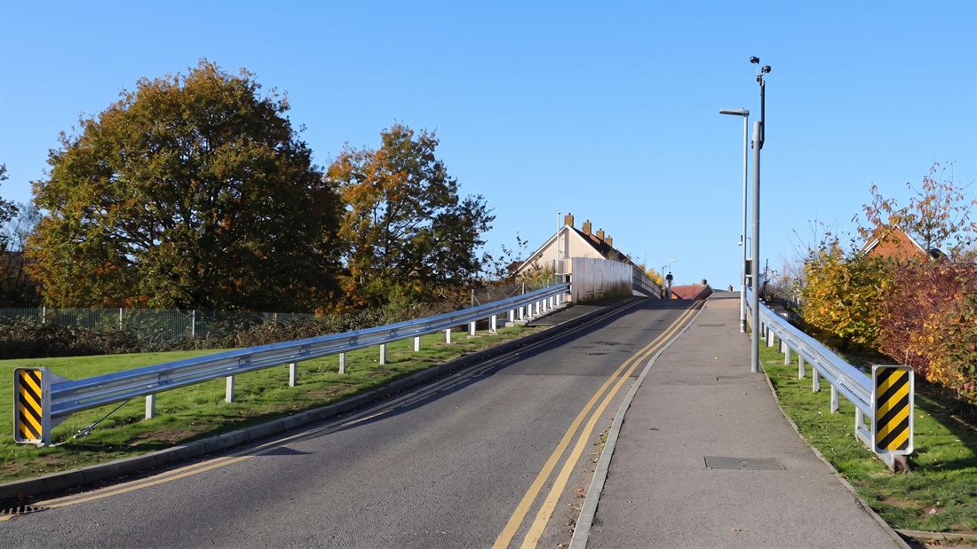 The Bluebell Road bus gate approach, showing the road restraint system installed along both bridge approaches and the signal head on the far side.